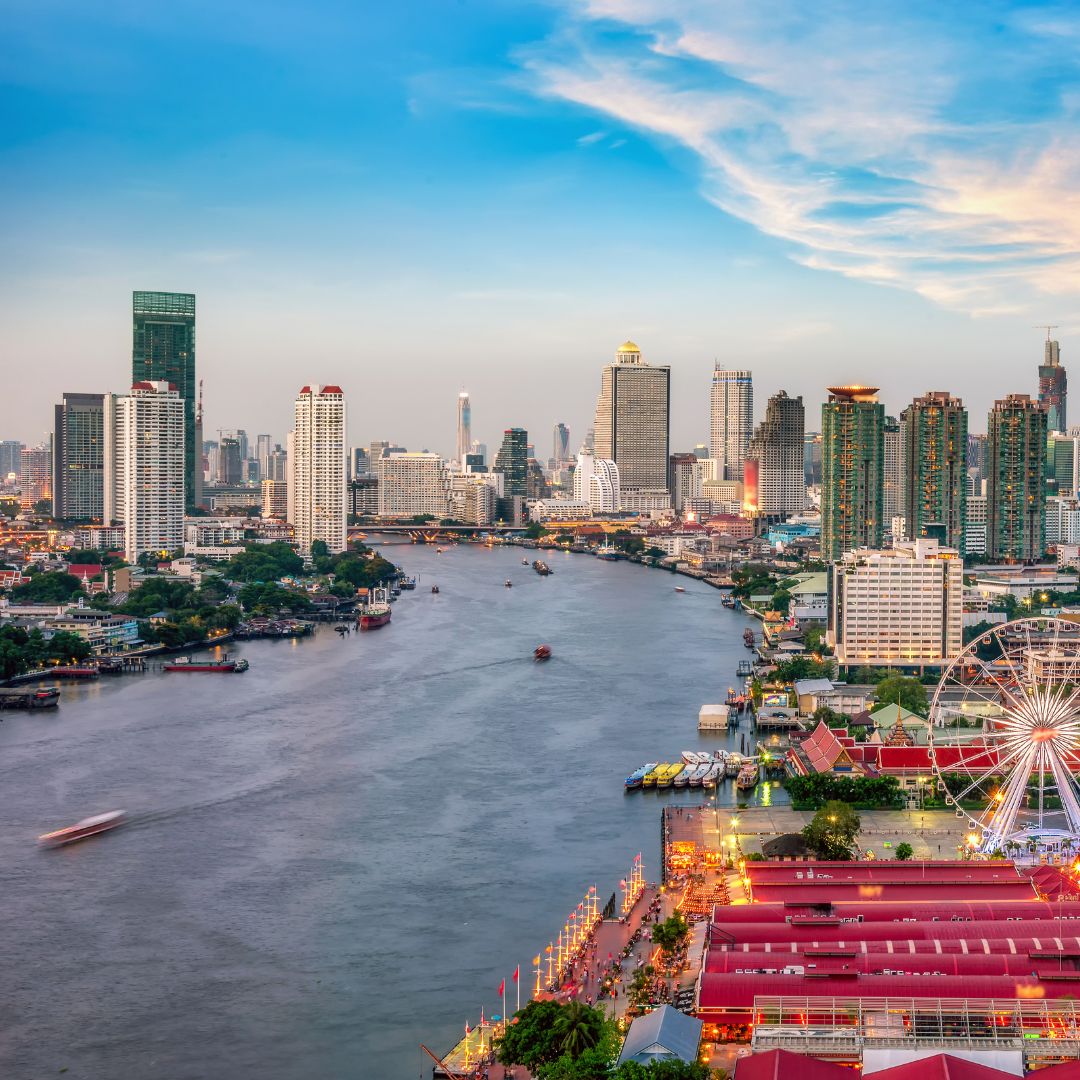The Bangkok skyline at dusk along the Chao Phraya River, with high-rise towers and temples, the commercial heart of Thailand and gateway to Southeast Asia for private jet charter.