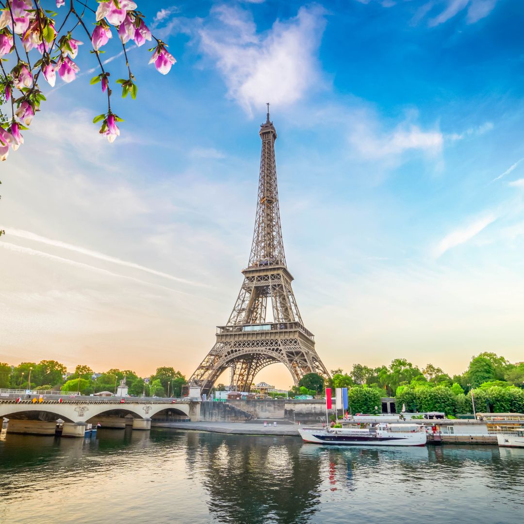 Eiffel Tower framed by spring blossoms with the Seine River at sunset, a classic private jet charter destination.