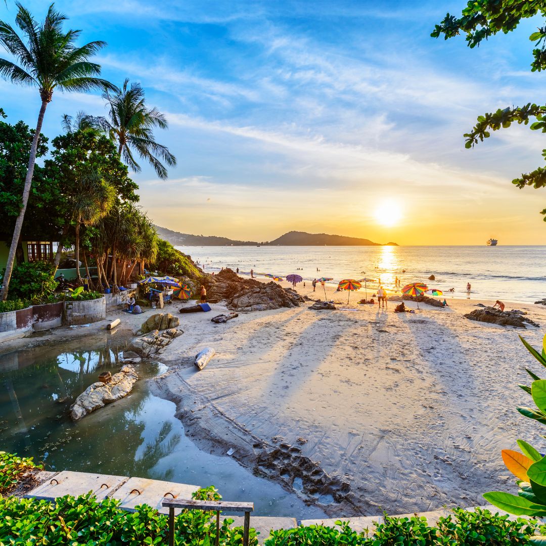A beach and resort on the Andaman Sea coast of Phuket at dusk, with limestone islands offshore, Thailand's premier luxury beach destination for private jet charter.